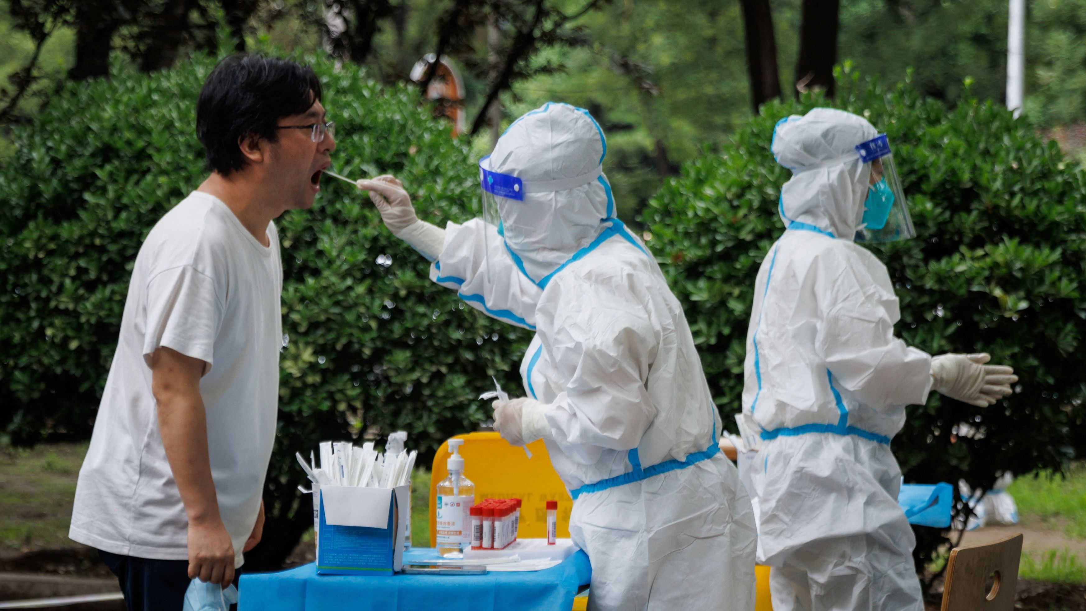 A medical worker takes a swab sample at a nucleic acid testing station in Beijing on July 6.