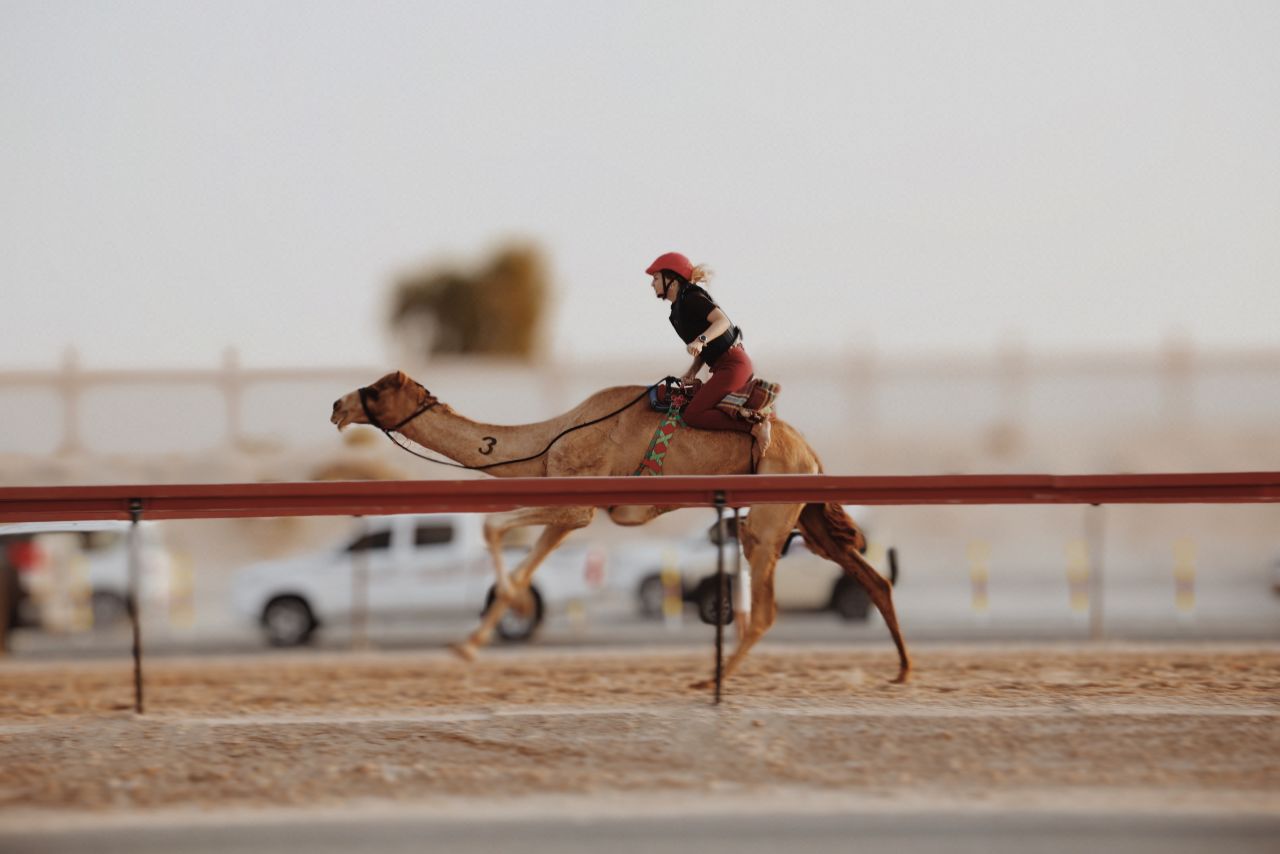 A rider from the Arabian Desert Camel Riding Center competing in a women's race.