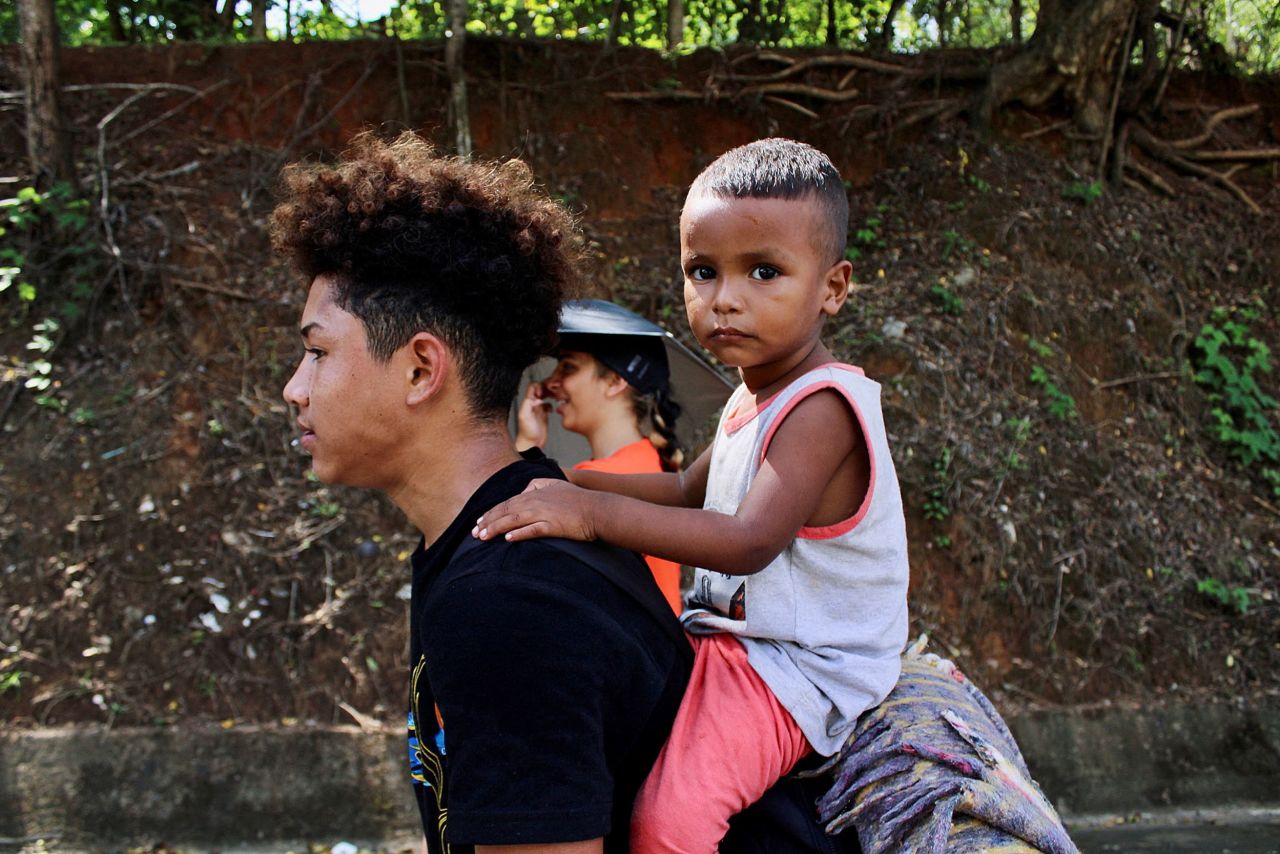 A man carries his son in Tapachula, Mexico, as he walks along with other migrants in a caravan heading to the US border on Friday, July 1.