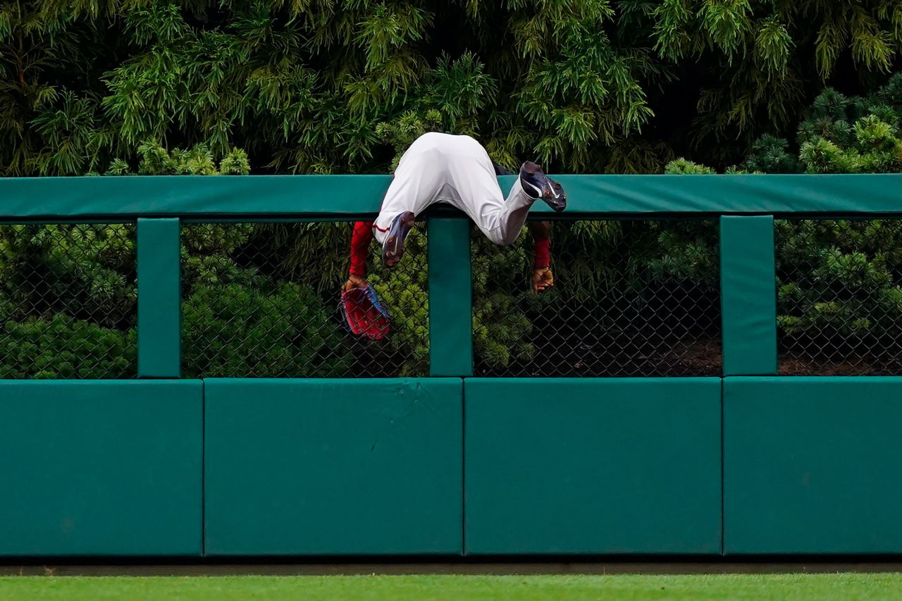Washington center fielder Victor Robles hangs over a fence after trying to reach a home run hit by Philadelphia's Kyle Schwarber on Tuesday, July 5.