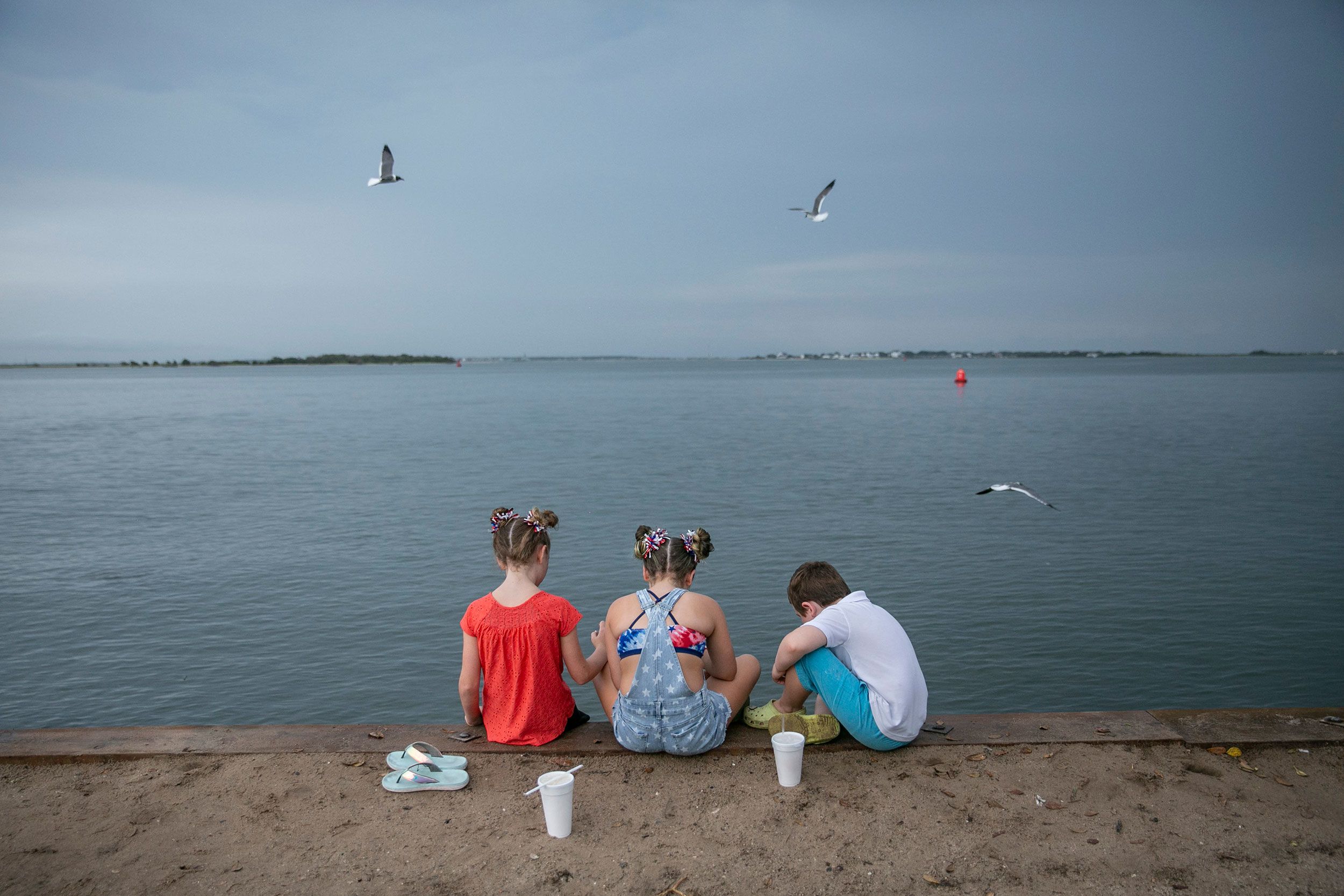 Children eat on a seawall after the annual Independence Day Parade in Southport, North Carolina, on Monday, July 4.