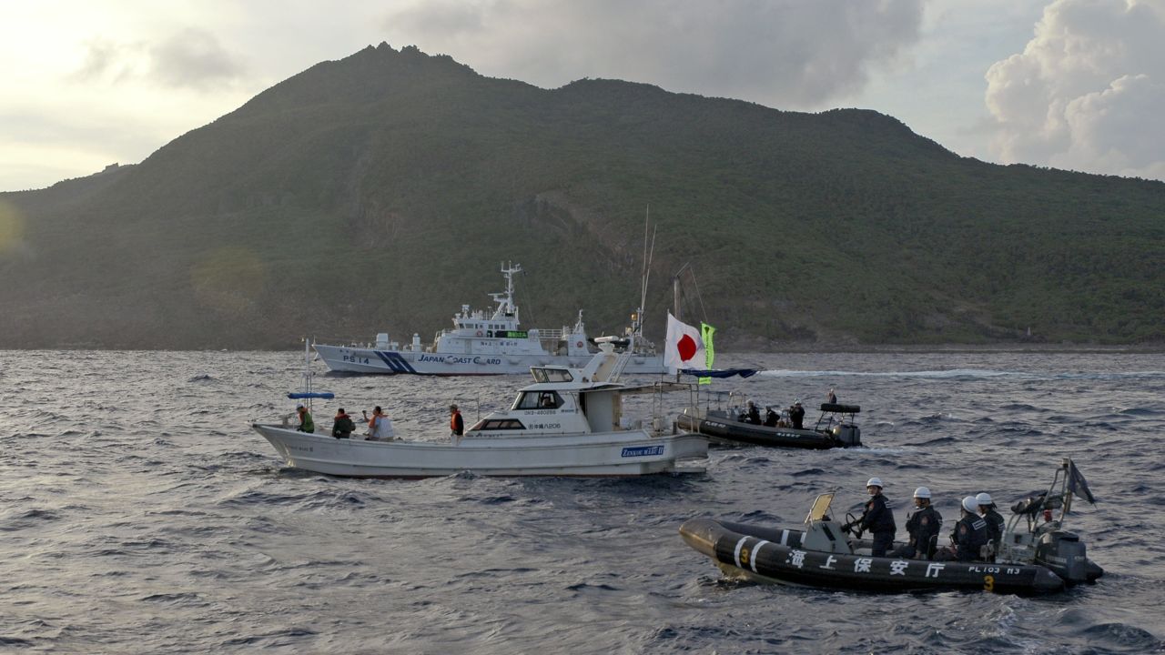 Japanese Coast Guard vessels, rear and right, sail alongside a Japanese activists' fishing boat, center with a flag, near a group of disputed islands called Diaoyu by China and Senkaku by Japan, in August 2013. 
