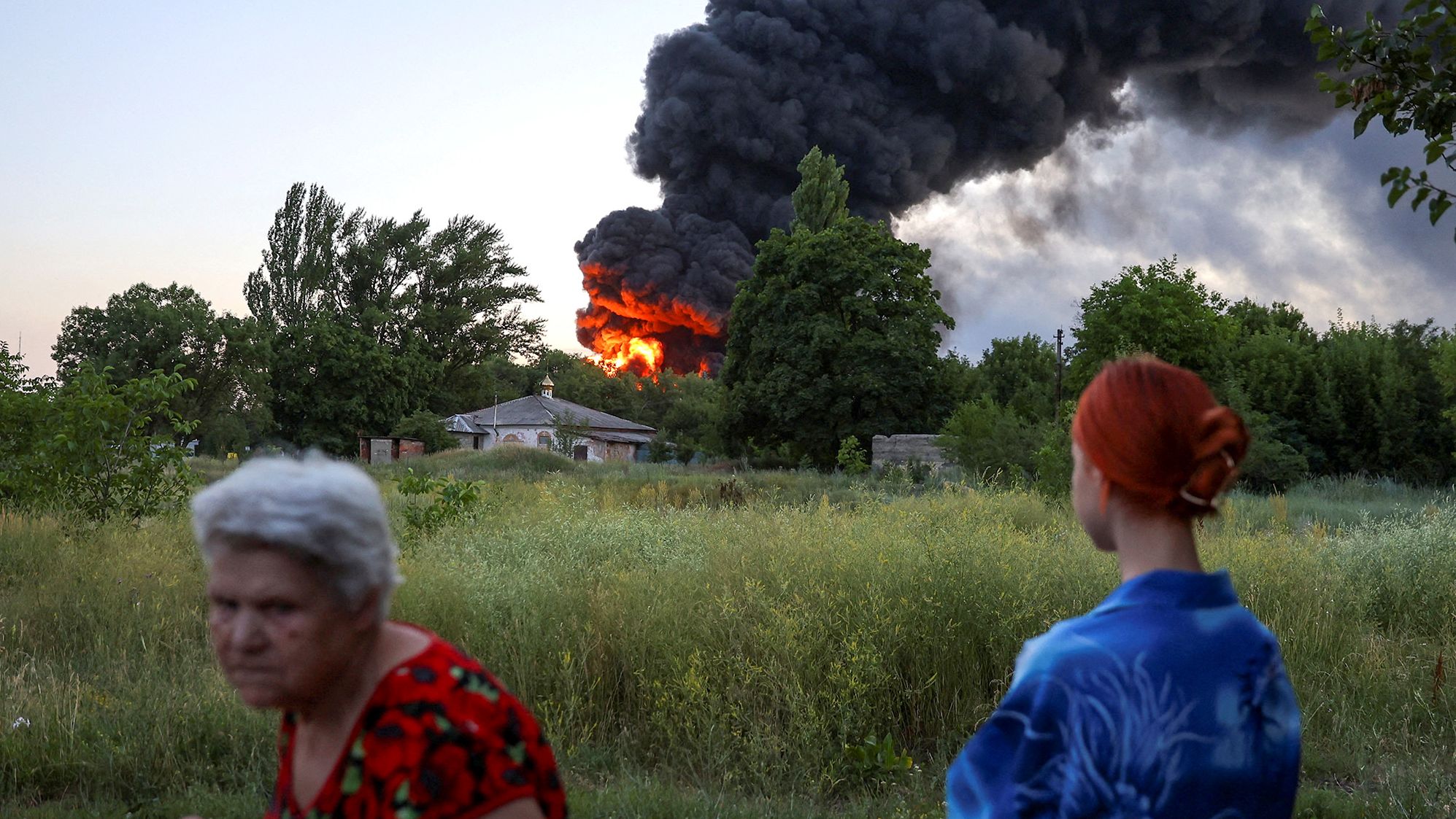 Local residents look on as smoke rises after shelling in Donetsk, Ukraine, on July 7.