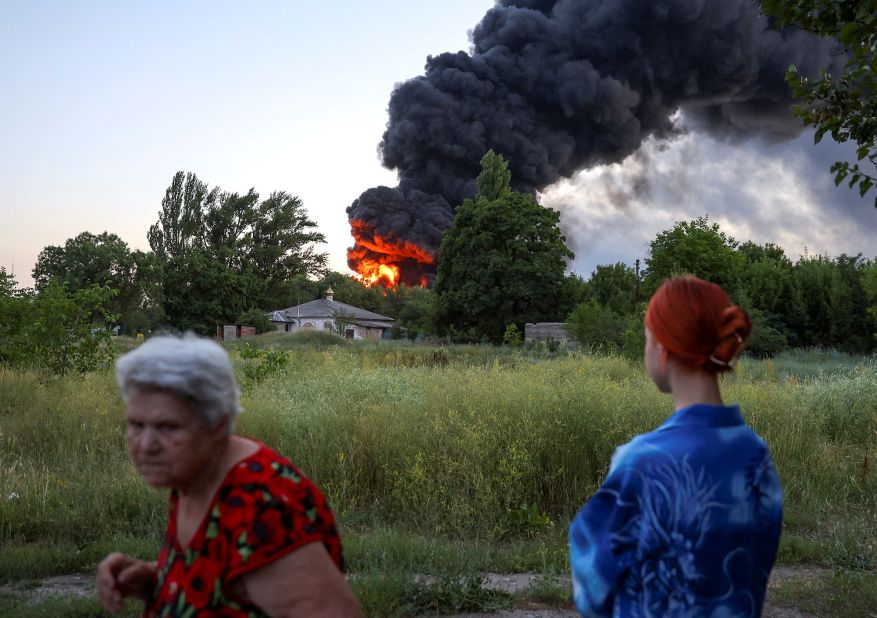 Local residents look on as smoke rises after shelling in Donetsk, Ukraine, on July 7.