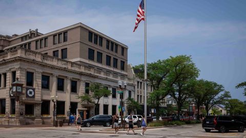 People walk by an American flag flying at half-staff on Central Avenue in Highland Park on July 5.