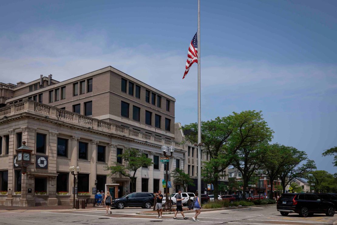 People walk by an American flag flying at half-staff on Central Avenue in Highland Park on July 5.