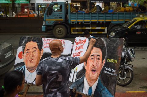 An artist in Mumbai, India, puts the final touches on a couple of Abe tribute paintings.