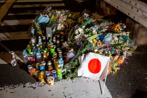A Japanese national flag is placed next to flowers at a site outside of Yamato-Saidaiji Station where former Japanese prime minister Shinzo Abe was shot.