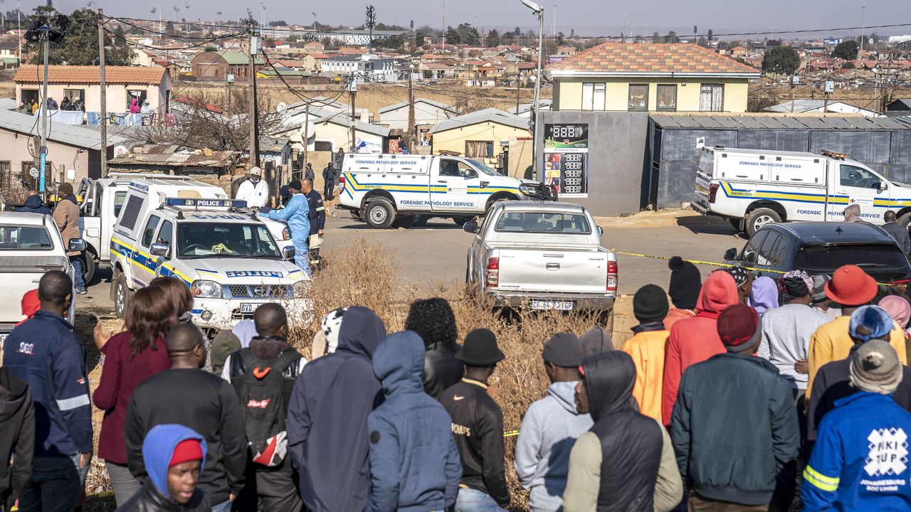 People gather at the scene of an overnight bar shooting in Soweto, South Africa, Sunday July 10, 2022. 