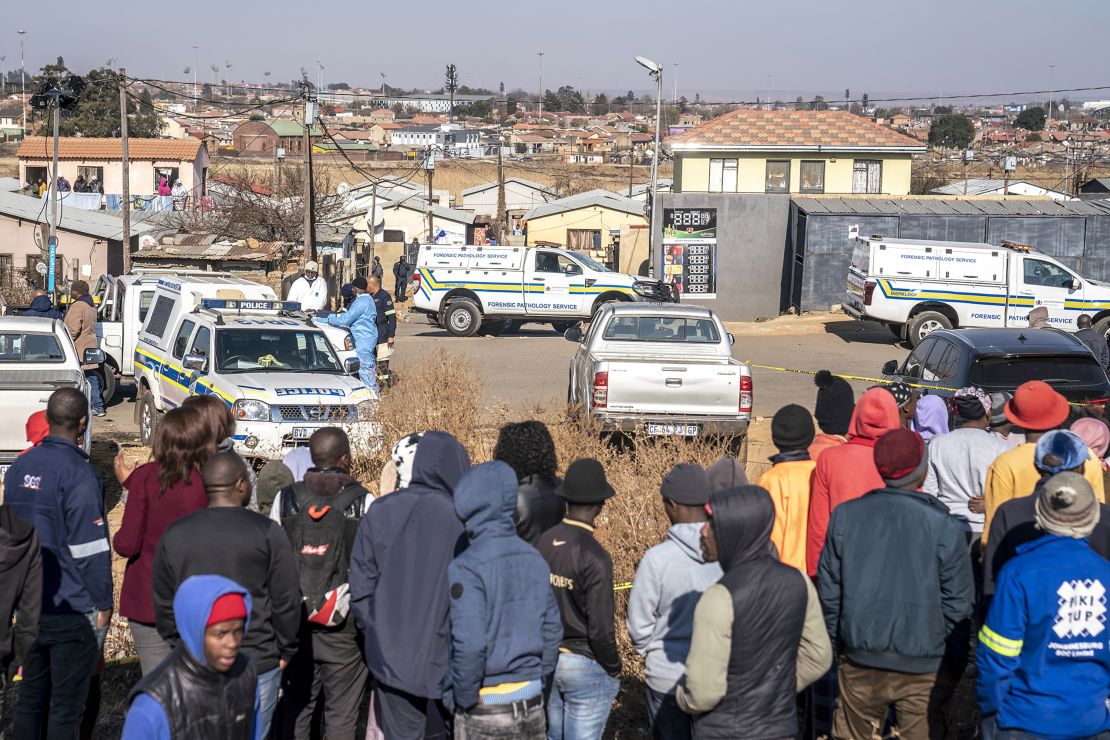 People gather at the scene of an overnight bar shooting in Soweto, South Africa, Sunday July 10, 2022.