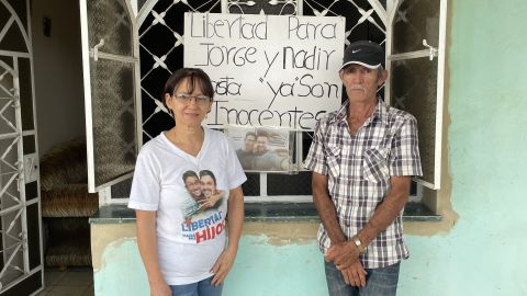 マルタとホルヘ・ペルドモは、2022年6月28日、キューバのサンホセデラスラハスにある自宅の看板の前に立っています。 