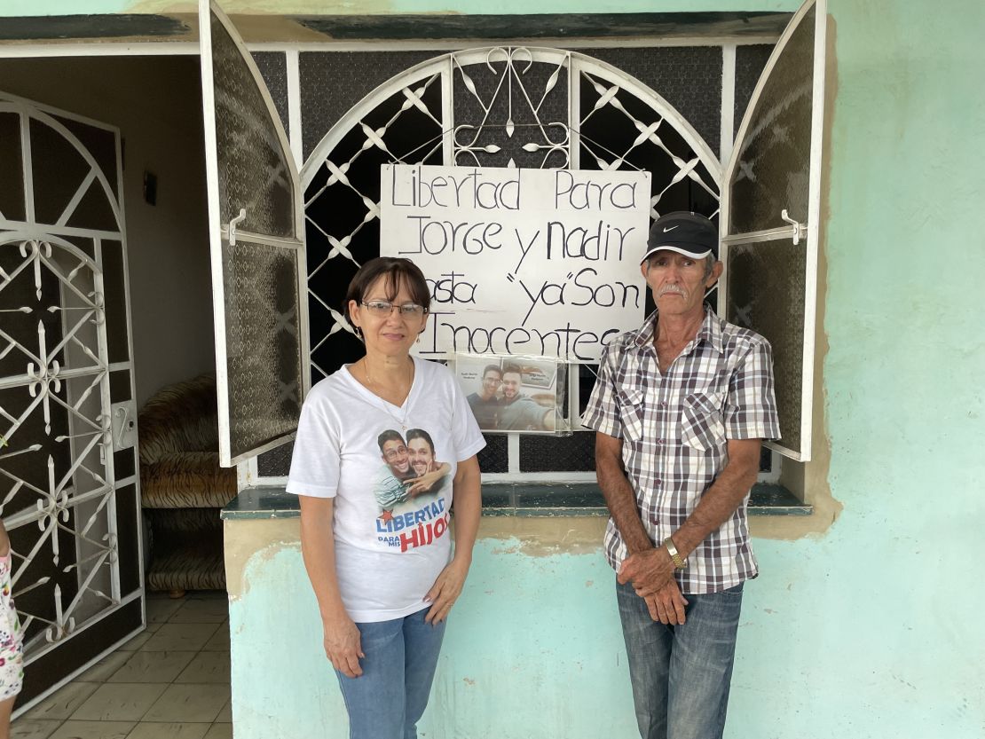 Marta and Jorge Perdomo stand in front of a sign on their home in San Jose de las Lajas, Cuba, on June 28, 2022. 