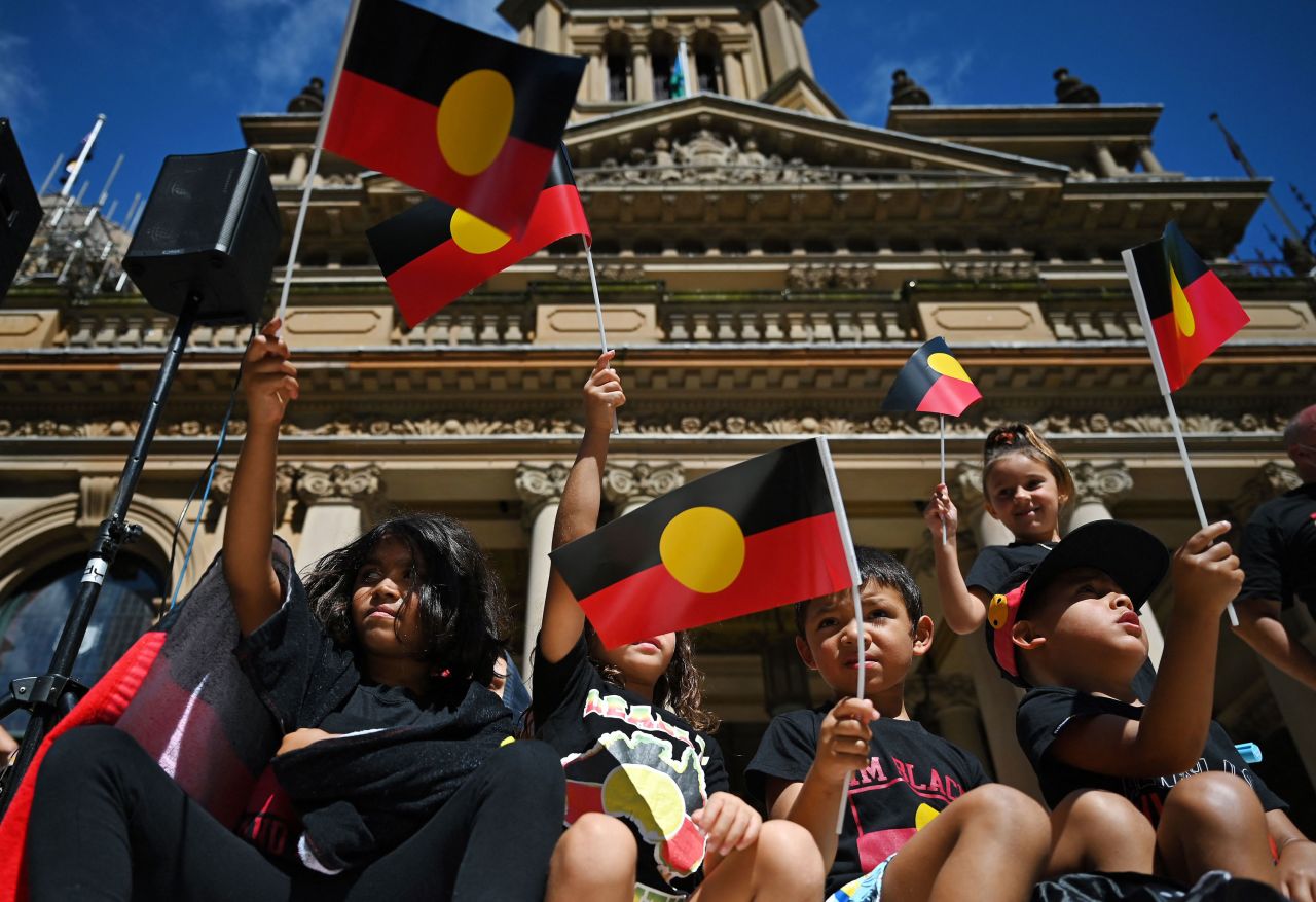 People wave the Australian Aboriginal flag as protesters take part in an "Invasion Day" demonstration on Australia Day in Sydney on January 26, 2022.