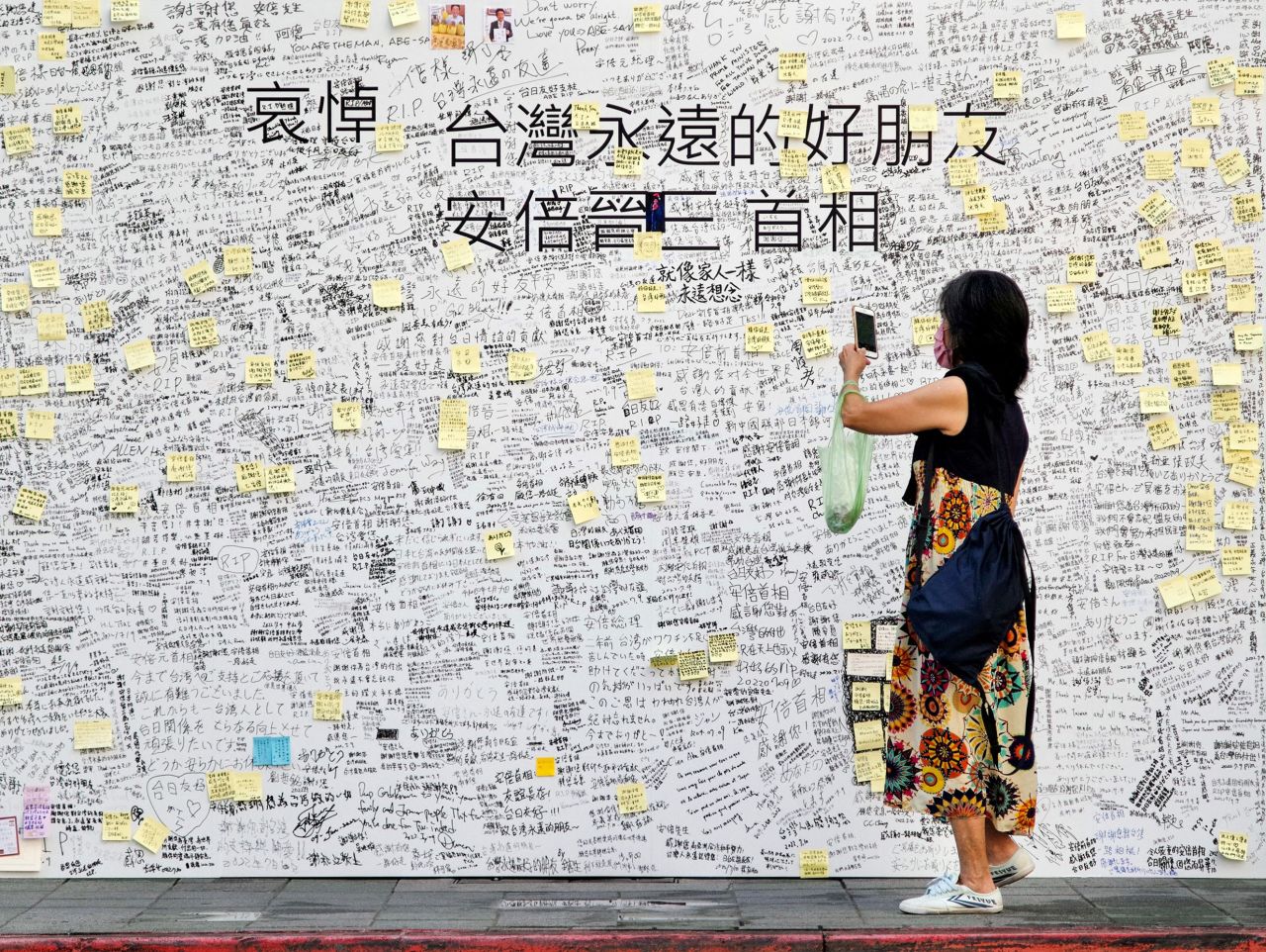 A woman takes a photograph of condolence messages for former Japanese prime minister Shinzo Abe in front of the Japan-Taiwan Exchange Association office in Taipei, Taiwan, on July 11.