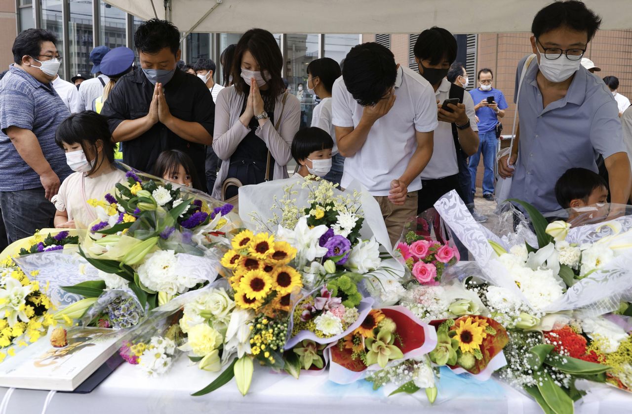 People pray after placing flowers at a makeshift memorial in Nara, Japan, on July 10, near the location where former Japanese Prime Minister Shinzo Abe was fatally shot.