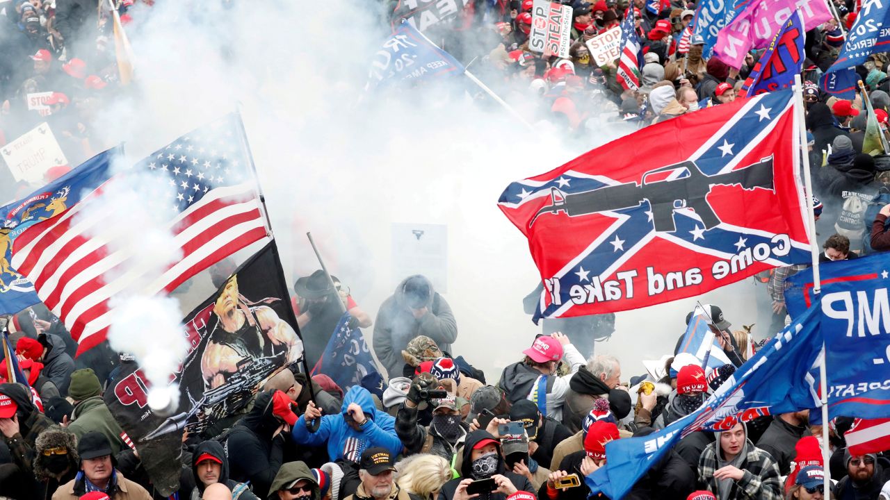 Tear gas is released into a crowd of protesters, with one wielding a Confederate battle flag that reads, "Come and Take It," January 6, 2021.