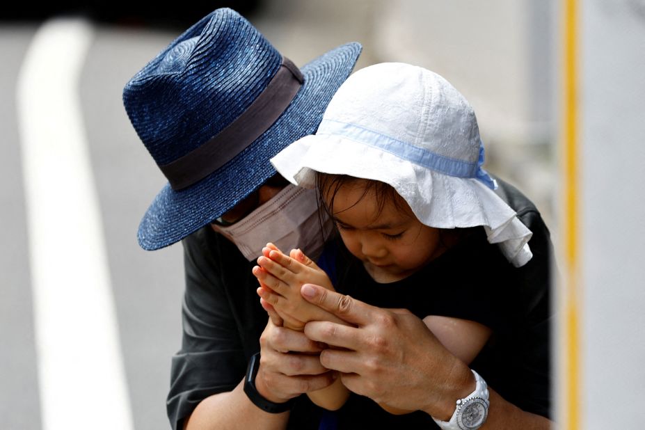 A man and his three-year old granddaughter pray as they mourn former Japanese Prime Minister Shinzo Abe, outside his residence in Tokyo, Japan on Sunday, July 10, 2022. 
