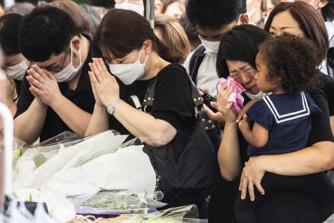 A woman cries as other mourners pray at the Zojoji Temple during the funeral of former Japanese Prime Minister Shinzo Abe in Tokyo, Japan, Tuesday, July 12, 2022.