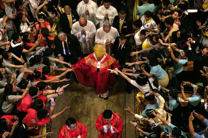 The Pope walks out from Assumption Cathedral as young people reach out to touch him in Bangkok.