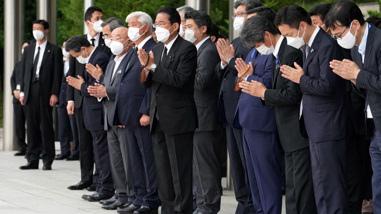 Japan's Prime Minister Fumio Kishida, officials and employees offer prayers outside the Prime Minister's Office in Tokyo on July 12.