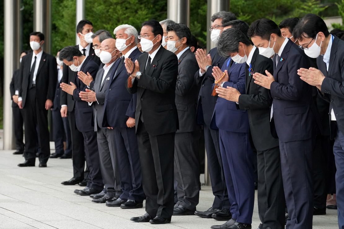 Japan's Prime Minister Fumio Kishida, officials and employees offer prayers outside the Prime Minister's Office in Tokyo on July 12.