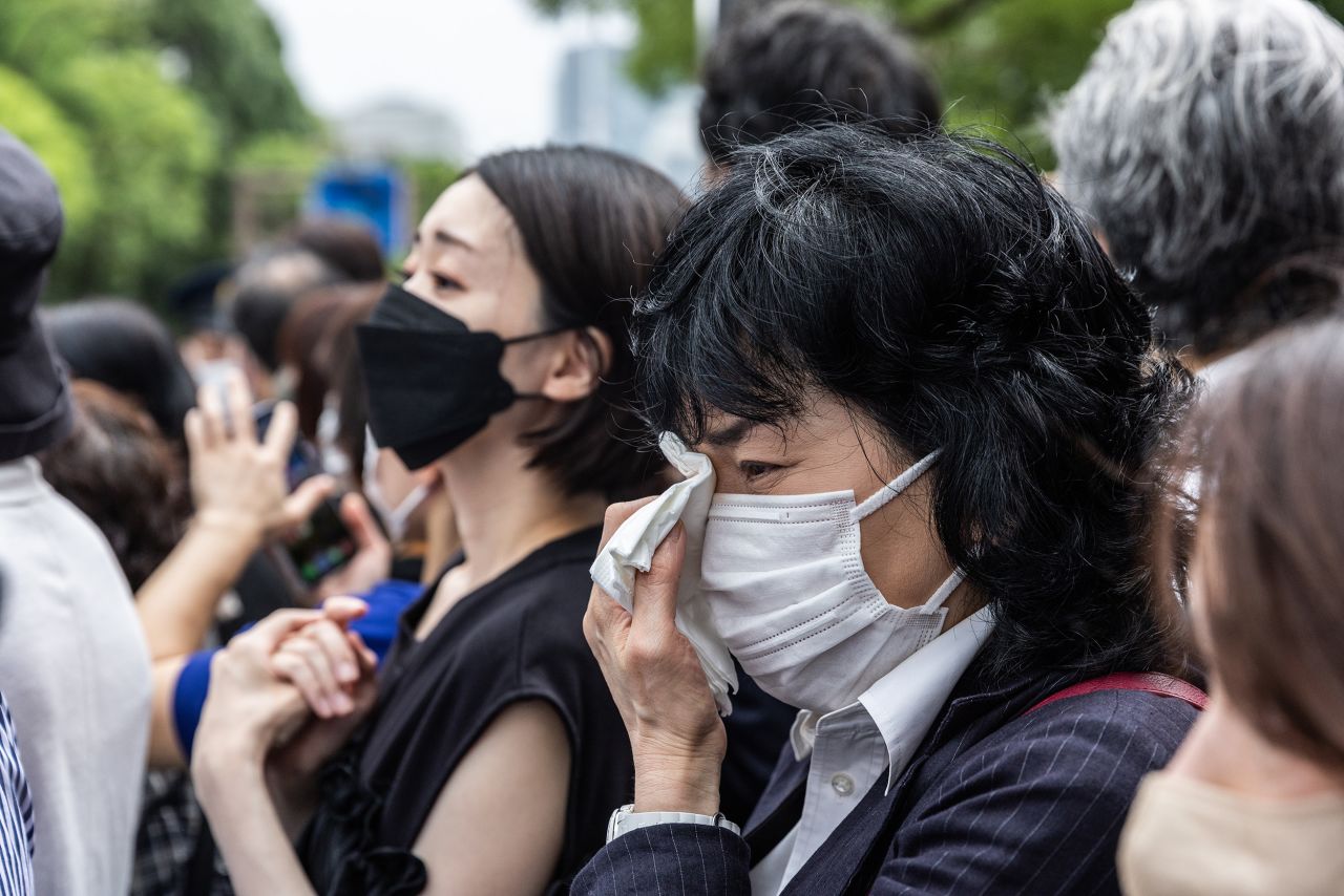 Mourners react after the hearse carrying the body of former Prime Minister Shinzo Abe drives by after his funeral in Tokyo, Japan, on July 12.