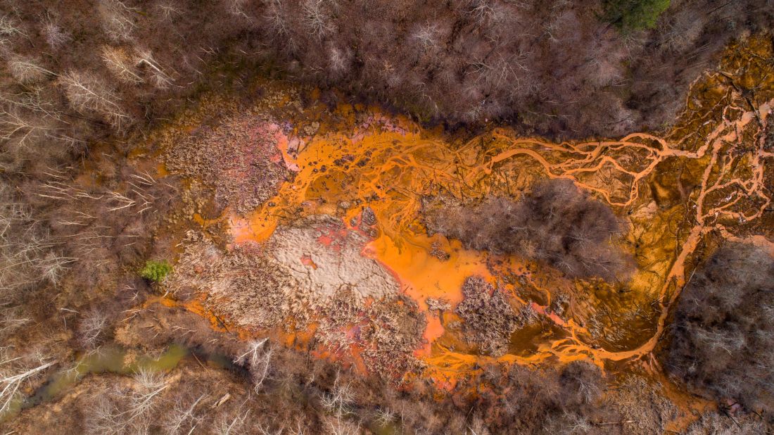 Acid mine drainage (AMD) is the overflow of acidic wastewater from underground mines and has a high concentration of sulfuric acid and dissolved iron,  which gives the runoff an orange coloring. Aquatic life struggles to survive in the acidic waters. Pictured, an AMD site in Oreton, Ohio.