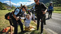 French gendarmes remove environmental protestors from the race route as their protest action temporarily immobilized the pack of riders during the 10th stage of the 109th edition of the Tour de France cycling race, 148,1 km between Morzine and Megeve, in the French Alps, on July 12, 2022. (Photo by Marco BERTORELLO / AFP) (Photo by MARCO BERTORELLO/AFP via Getty Images)