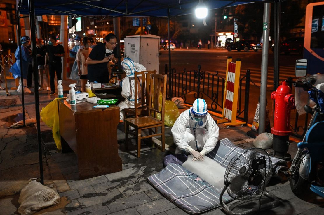 A health worker puts her hands on a block of ice in front of a fan to cool off at a Covid testing station in Shanghai on July 12.