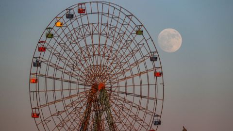 The moon rises behind a rundown Ferris wheel at an abandoned children's amusement park near al-Nayrab, a village ravaged by pro-government forces bombardment, in Syria's northwestern Idlib province on July 12, 2022 a day ahead of the July "buck supermoon". 