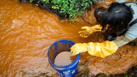 A volunteer collects acid mine drainage that is leaking into Sunday Creek in Truetown, Ohio,  October 22, 2021. 