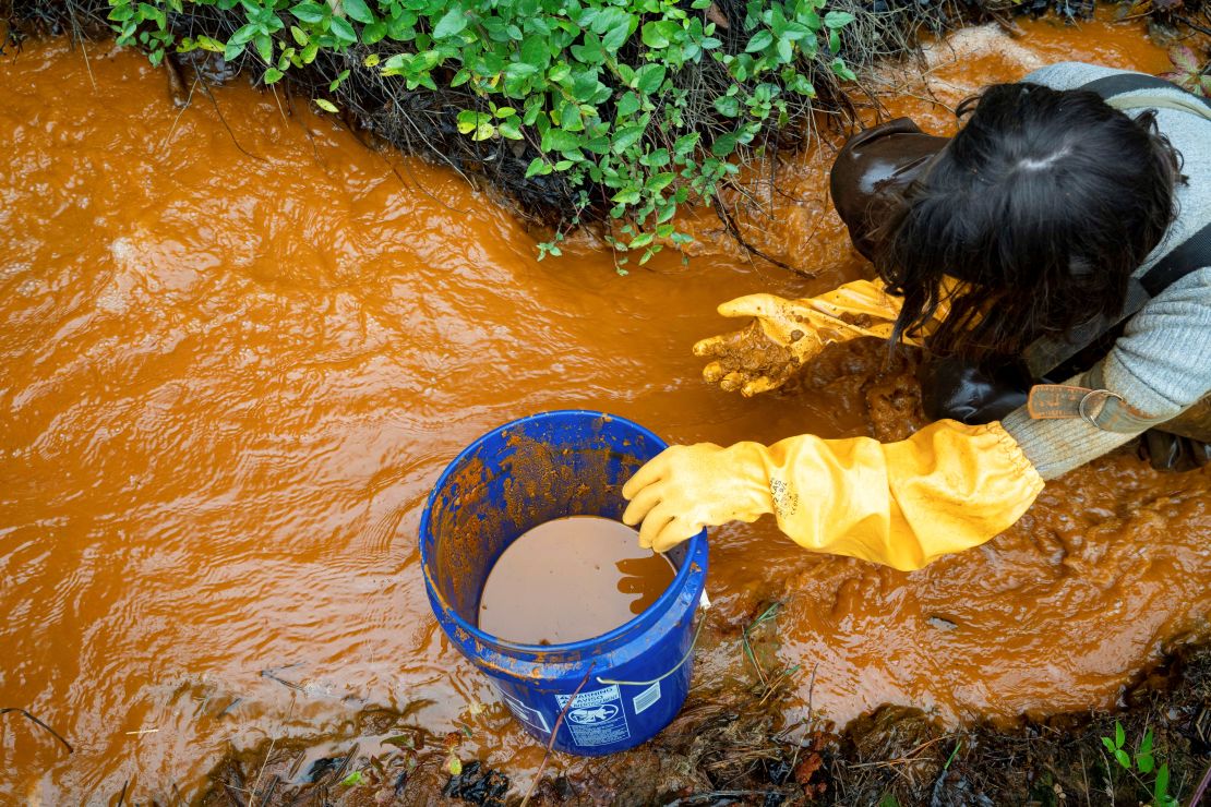 A volunteer collects acid mine drainage that is leaking into Sunday Creek in Truetown, Ohio,  October 22, 2021. 