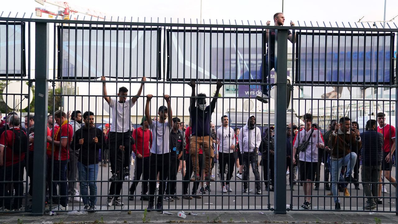 People try to climb gates outside the Stade de France as kick-off is delayed during the 2022 UEFA Champions League Final.