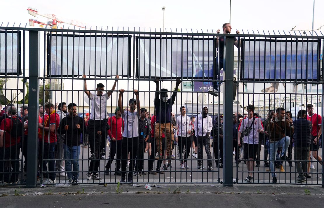 People try to climb gates outside the Stade de France as kick-off is delayed during the 2022 UEFA Champions League Final.