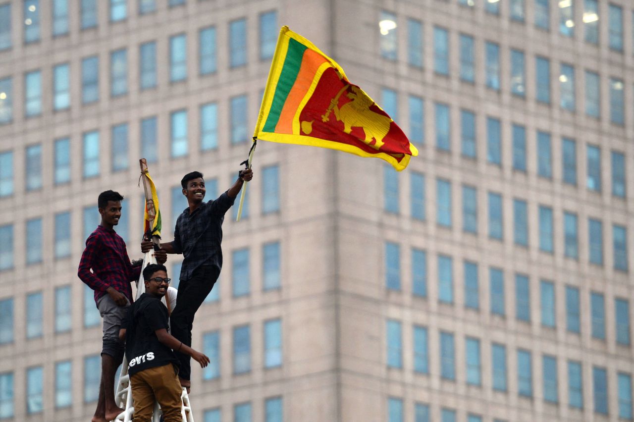 A man waves Sri Lanka's national flag after climbing a tower in Colombo on Monday.