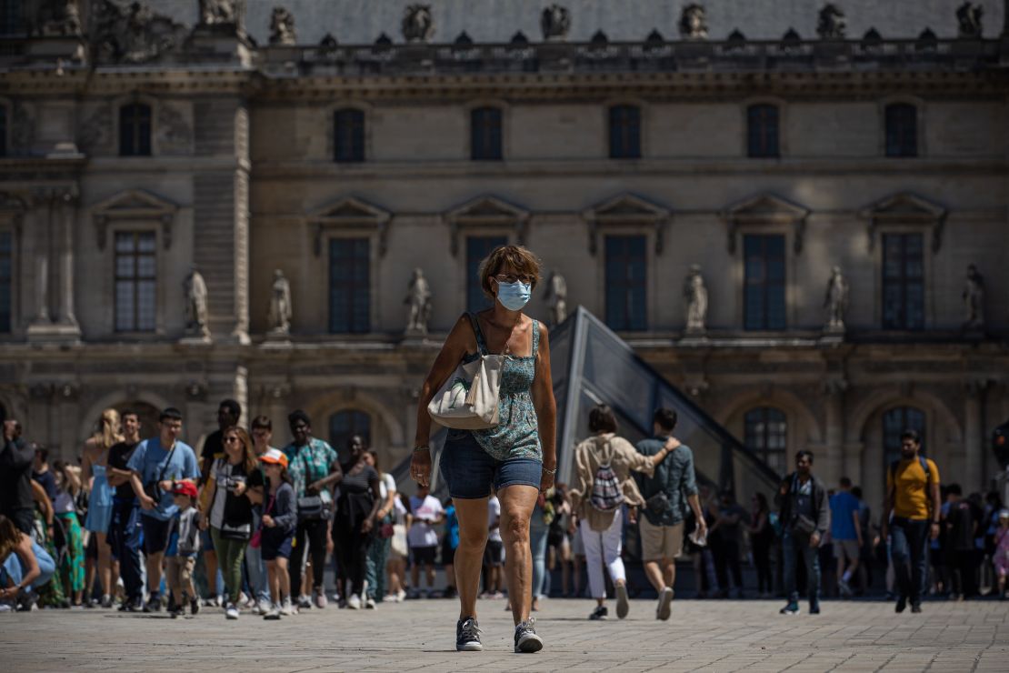 A woman wearing a face mask walks in front of the Louvre Museum in Paris, France, July 8.