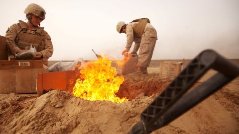 FILE PHOTO: U.S. Marines dispose of trash in a burn pit while stopping for a sandstorm to pass during a convoy to Patrol Base Sre Kalad in Khan Neshin District, Afghanistan March 3, 2012. Cpl. Alfred V. Lopez/U.S. Marines/Handout via REUTERS/File Photo