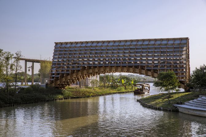 Designed by LUO Studio, this timber footbridge stretches across a waterway in Jiangmen, in China's Guangdong province. The arched shape allows fishing boats to pass beneath, while the bridge's covered internal corridor offers protection from the sun and rain.