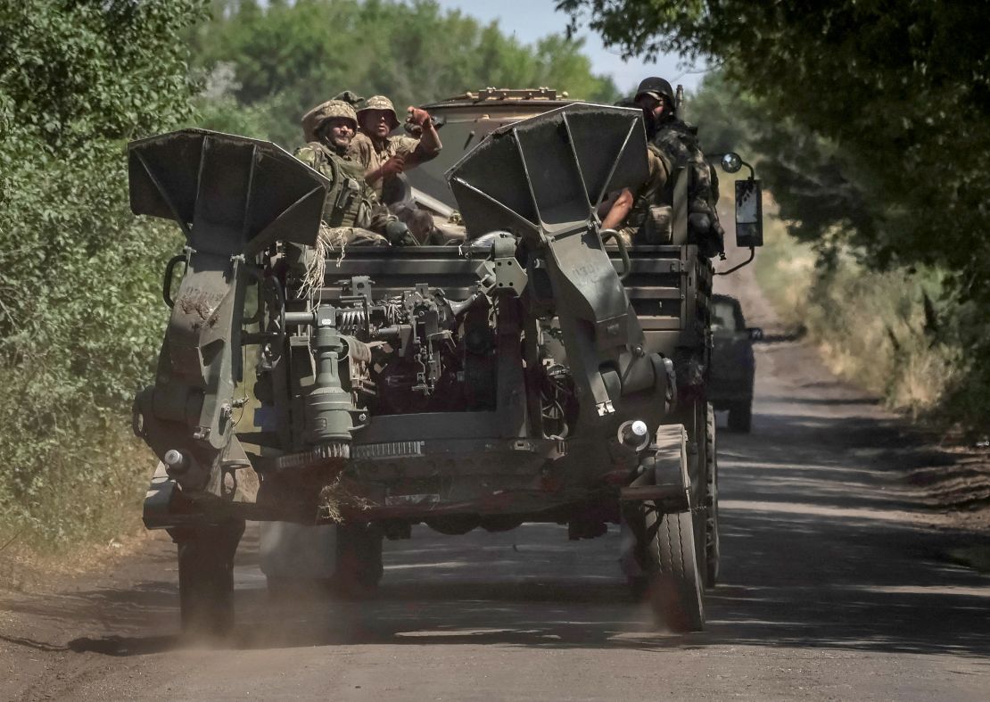 Ukrainian servicemen ride on a military vehicle as they tow an M777 towed 155 mm howitzer near the front line, amid Russia's attack on Ukraine, in the Donbas region.