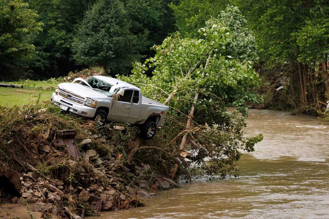 A truck sits on the edge of a river, Thursday, July 14, 2022, in Whitewood, Virginia, after being swept away in a flash flood.