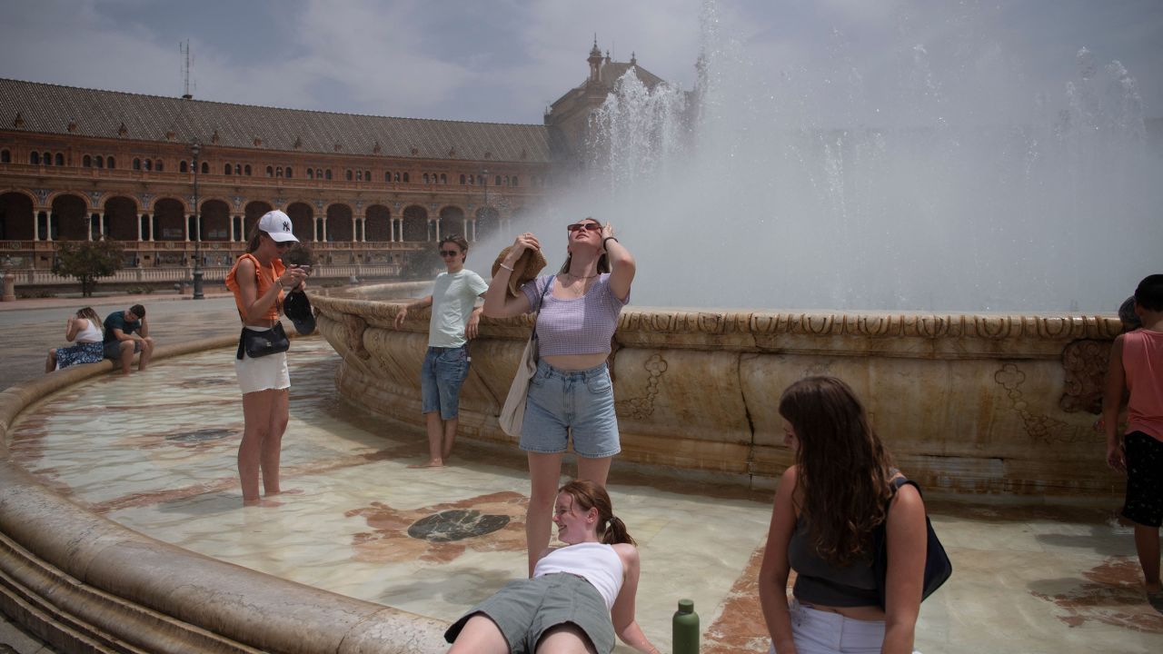 People cool off with a fountain's water during a heat wave in Seville, Spain on July 12.