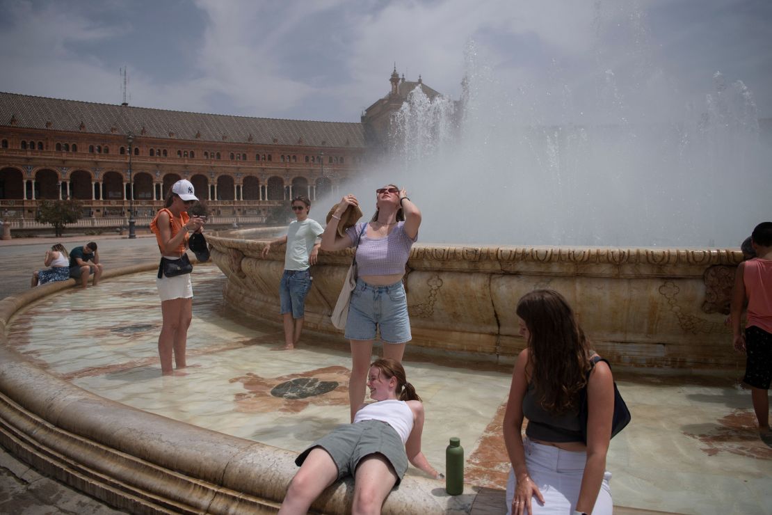 People cool off with a fountain's water during a heat wave in Seville, Spain on July 12.