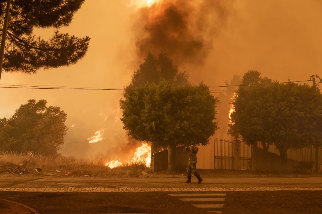 A member of the armed forces walks near a forest fire in Palmela, Portugal on July 13. The fire is currently close to a petrol station. In an effort to save their lives, some people and animals are being evacuated.