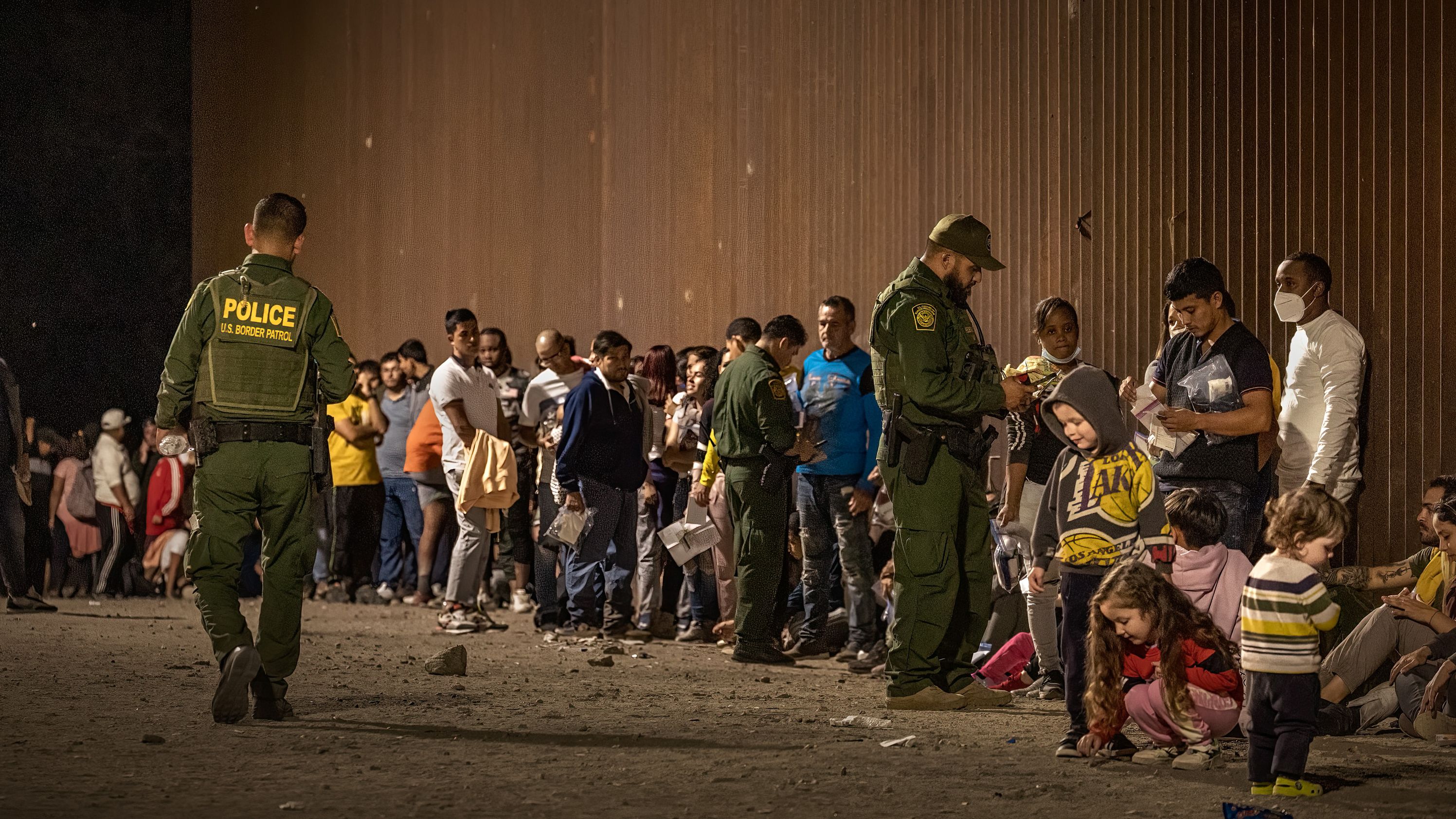 US Border Patrol agents check for identification of immigrants as they wait to be processed after crossing the border from Mexico on June 22, 2022, in Yuma, Arizona.