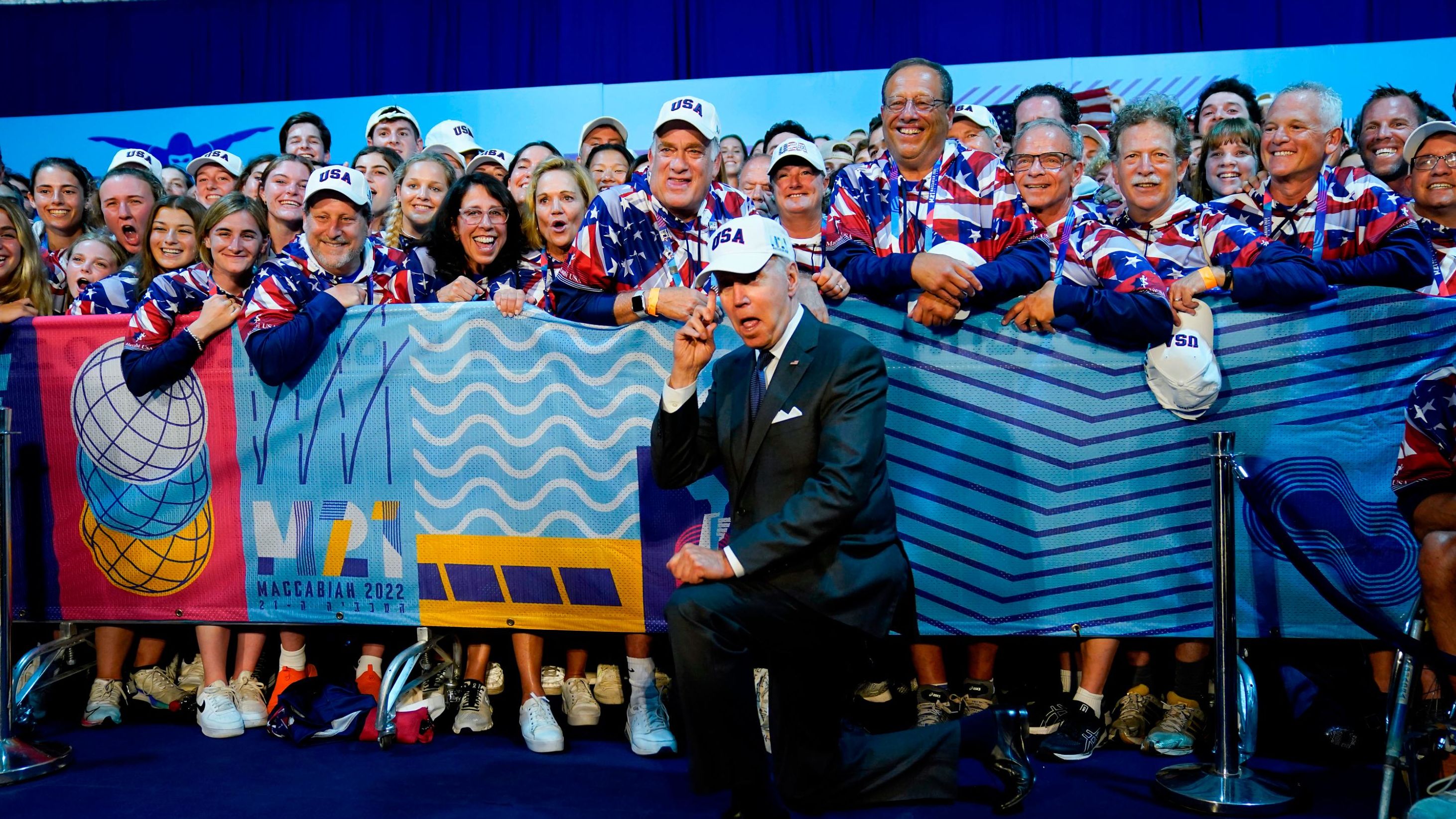 Biden points to his USA hat as he meets with US athletes competing in the Maccabiah Games, an international Jewish and Israeli multi-sport event, on Thursday. Biden also watched a portion of the opening ceremonies.