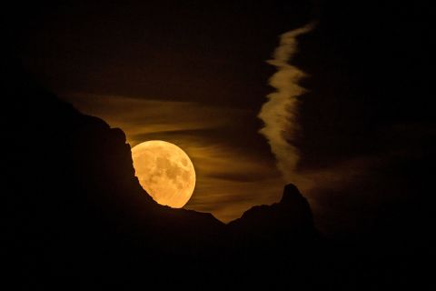 A full moon rises behind a mountain in the Swiss Alps on Wednesday, July 13.
