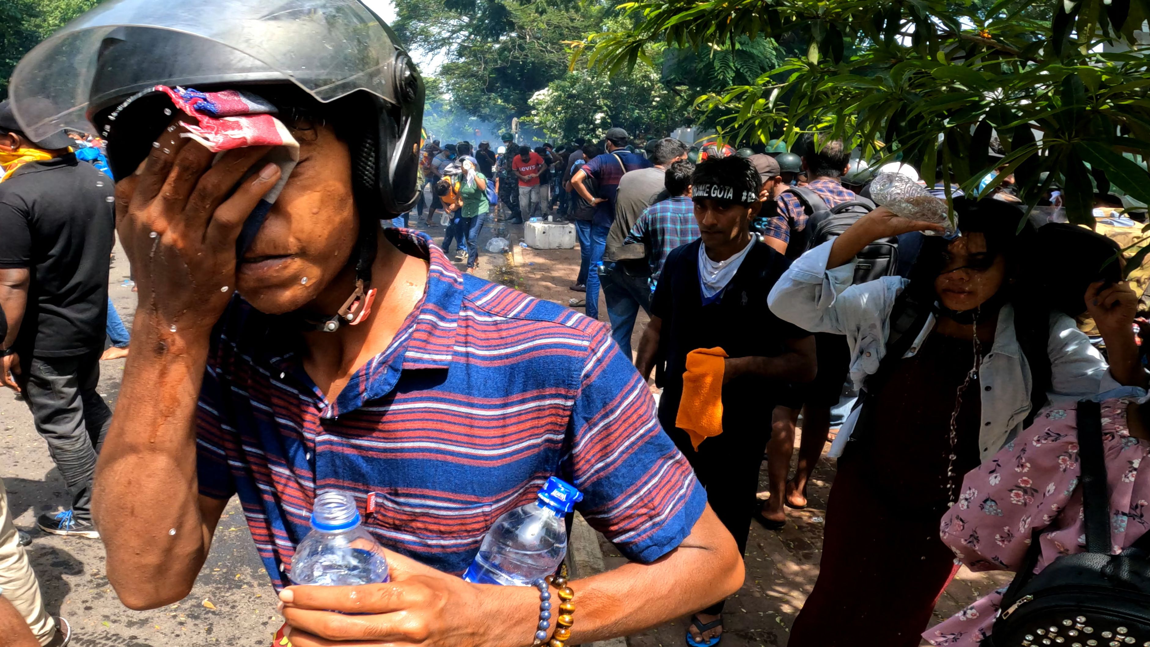 Sri Lankan anti-government protesters wipe their faces after being exposed to tear gas fired by police.