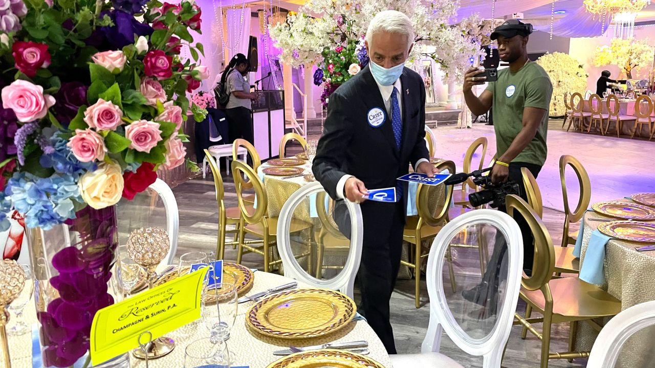 Crist places campaign bumper stickers around a table before the Haitian American Democratic Club of Broward luncheon in Fort Lauderdale, Florida, on July 10, 2022.