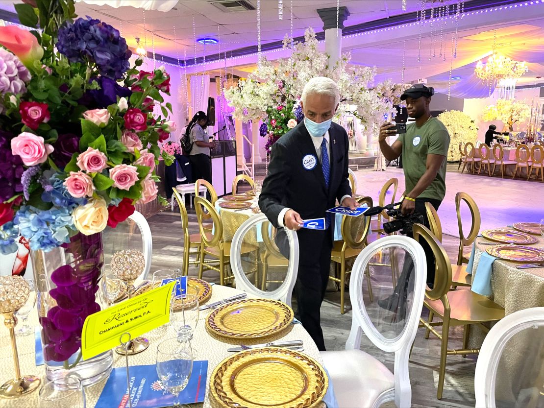 Crist places campaign bumper stickers around a table before the Haitian American Democratic Club of Broward luncheon in Fort Lauderdale, Florida, on July 10, 2022.