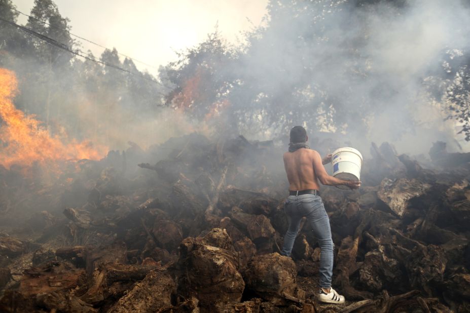 A local resident tries to stop flames from reaching houses in Figueiras, Portugal, on July 12.